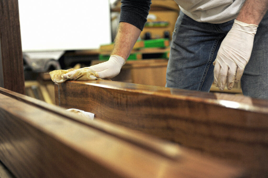 A STUDENT OILING COMPONENTS FOR A PIECE OF FURNITURE BEING MADE ON A LEARN FURNITURE MAKING COURSE AT ROWDEN ATELIER