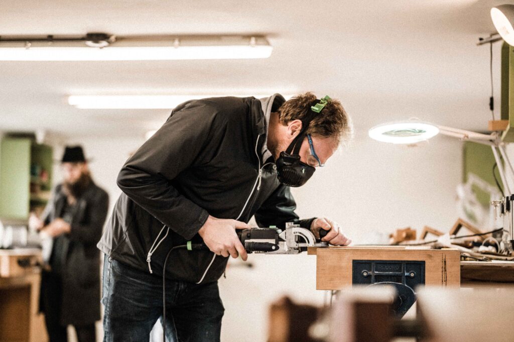 A STUDENT USING A DOMINO MACHINE AS PART OF A FURNITURE MAKING WOODWORKING COURSE AT ROWDEN ATELIER